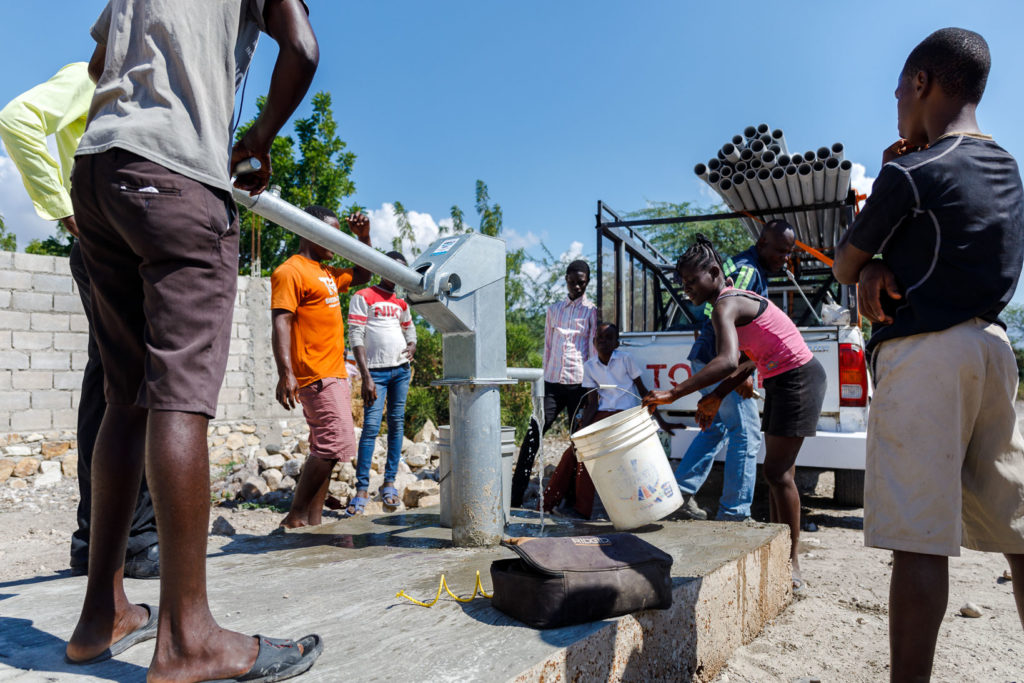 A young man pumps water at a newly installed water well.