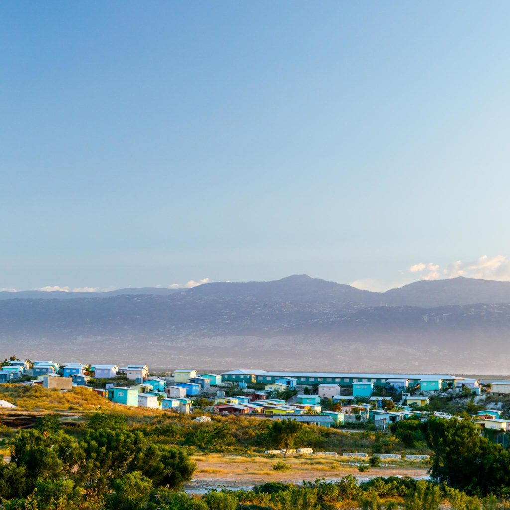 Golden light illuminates brightly colored buildings during evening in Port-au-Prince, Haiti.