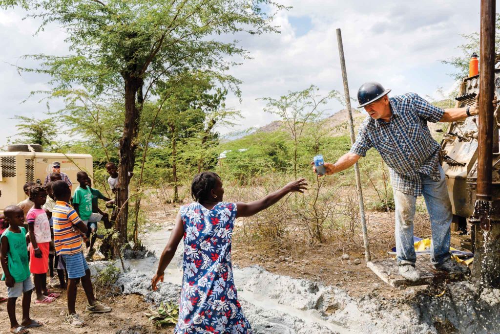 Curt passes a sample of water from a newly dug water well.