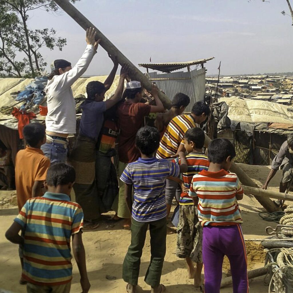 Missionaries and locals erect a wooden pole in the slums of Bangladesh.