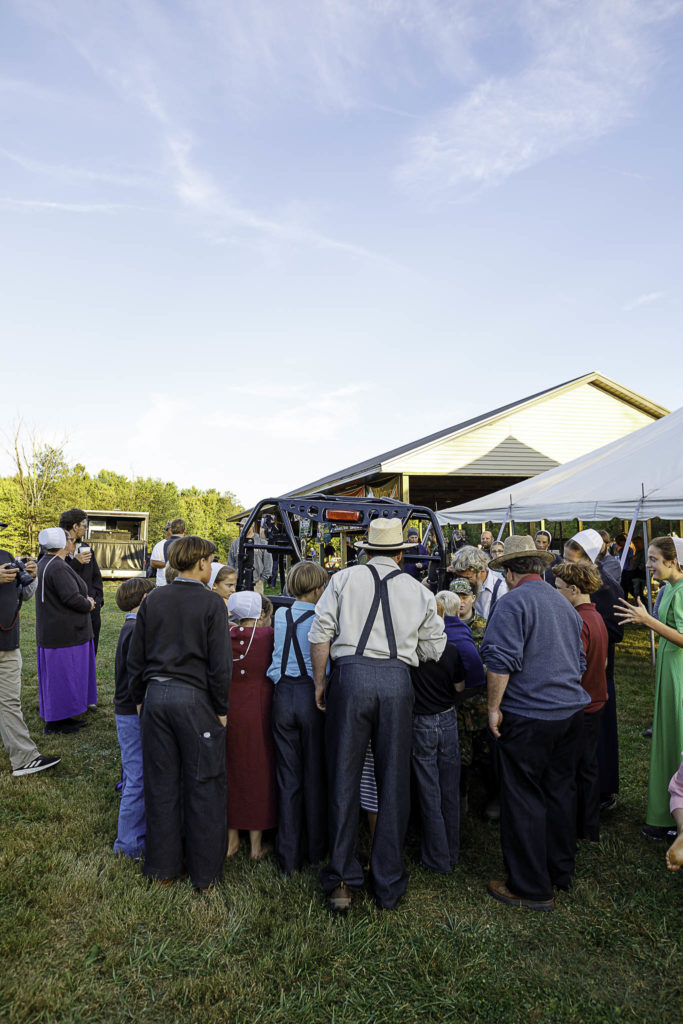 Excited spectators gather around a UTV to see what deer a young hunter shot in the woods.