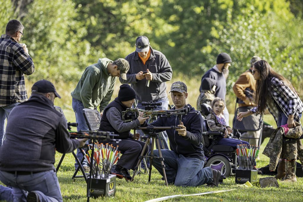 Volunteers assist young hunters with various disabilities in crossbow shooting practice.
