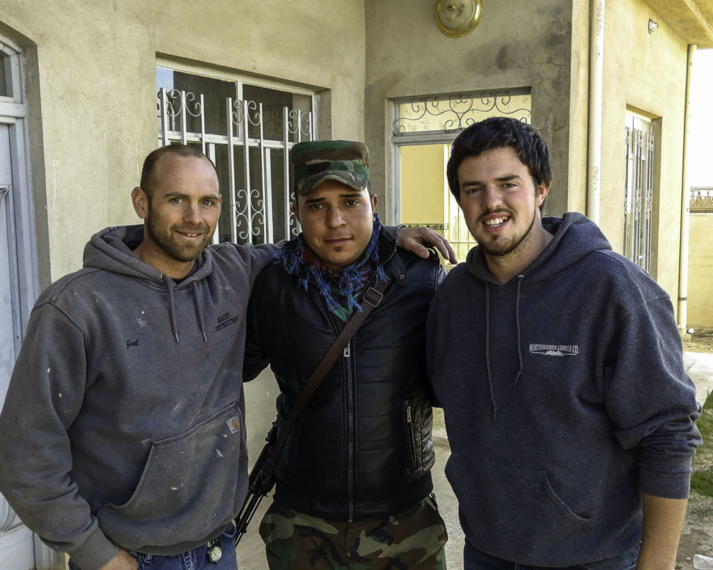 Two volunteer workers and soldier pose for photo