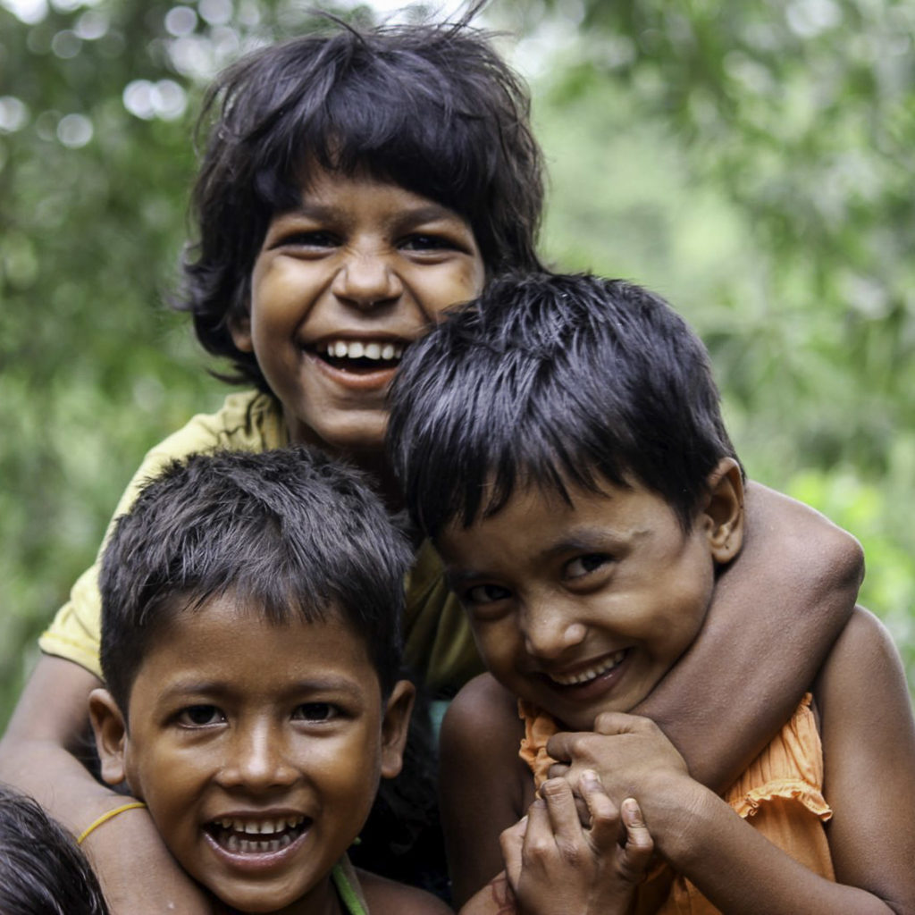 Three laughing children in a group hug.