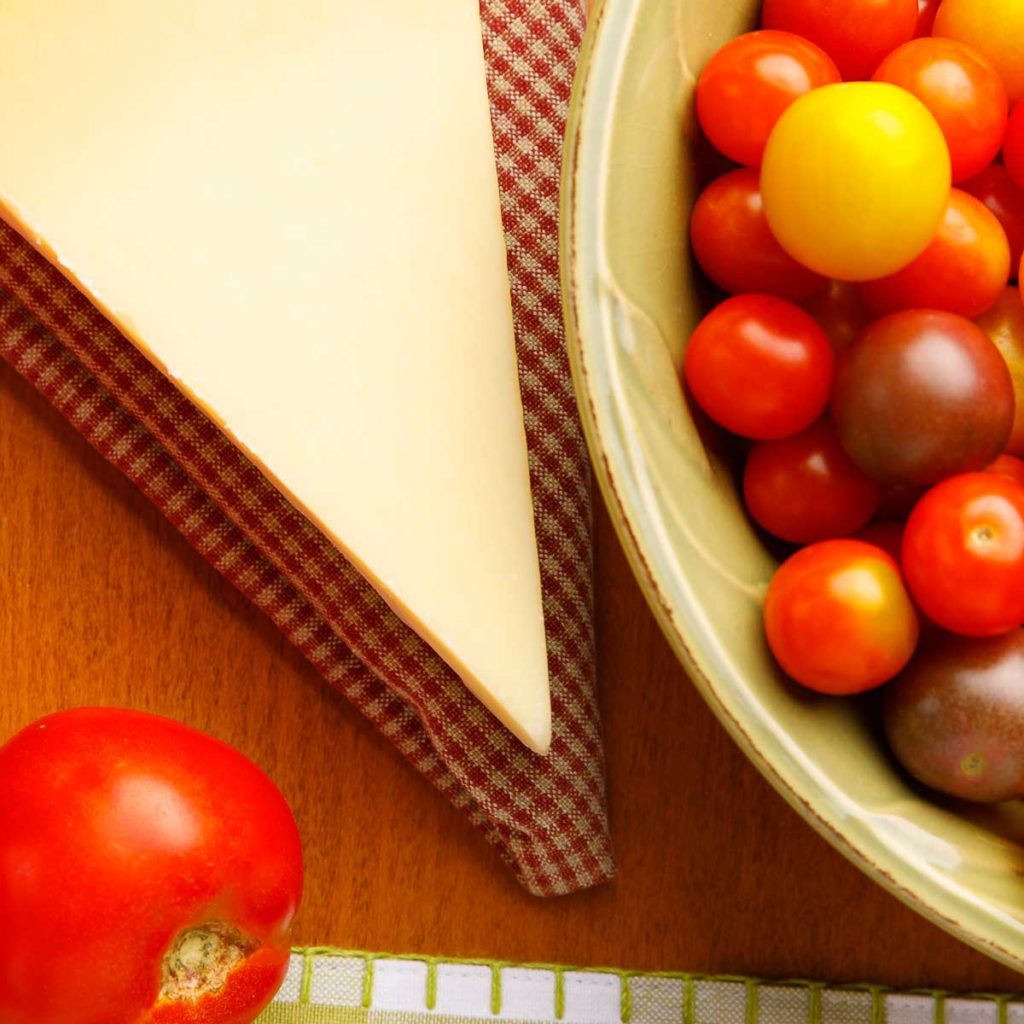Cheese cheery tomatoes in green bowl, checkered table cloth, ripe tomatoes