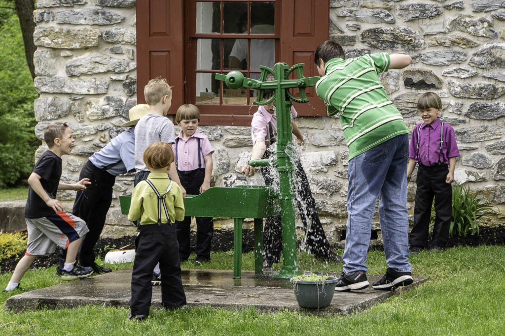Young Amish Children play with water at the Stoltzfus homstead in the summer