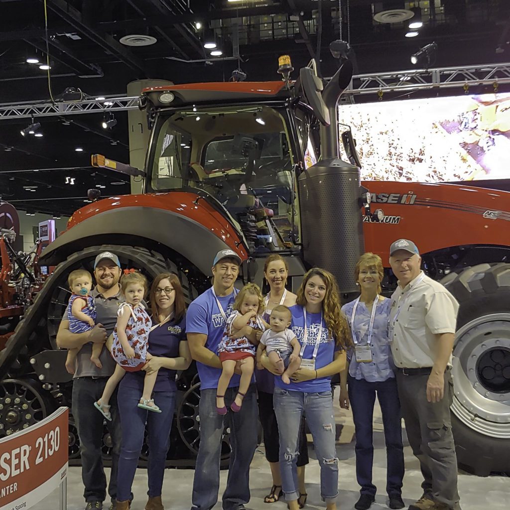 Welker family photo in front of Case IH tractor at trade show.