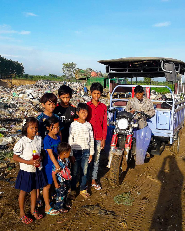 Cambodian children pose for a photo next to a garbage dump.