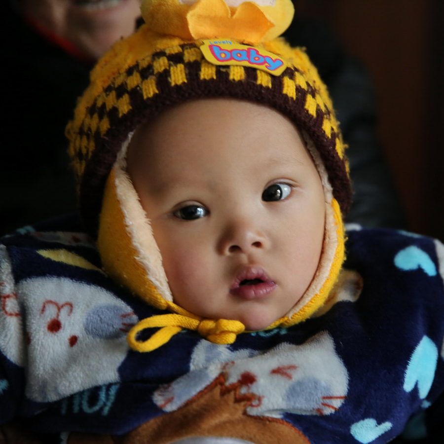 Young child dressed in winter clothing with yellow and brown hat.