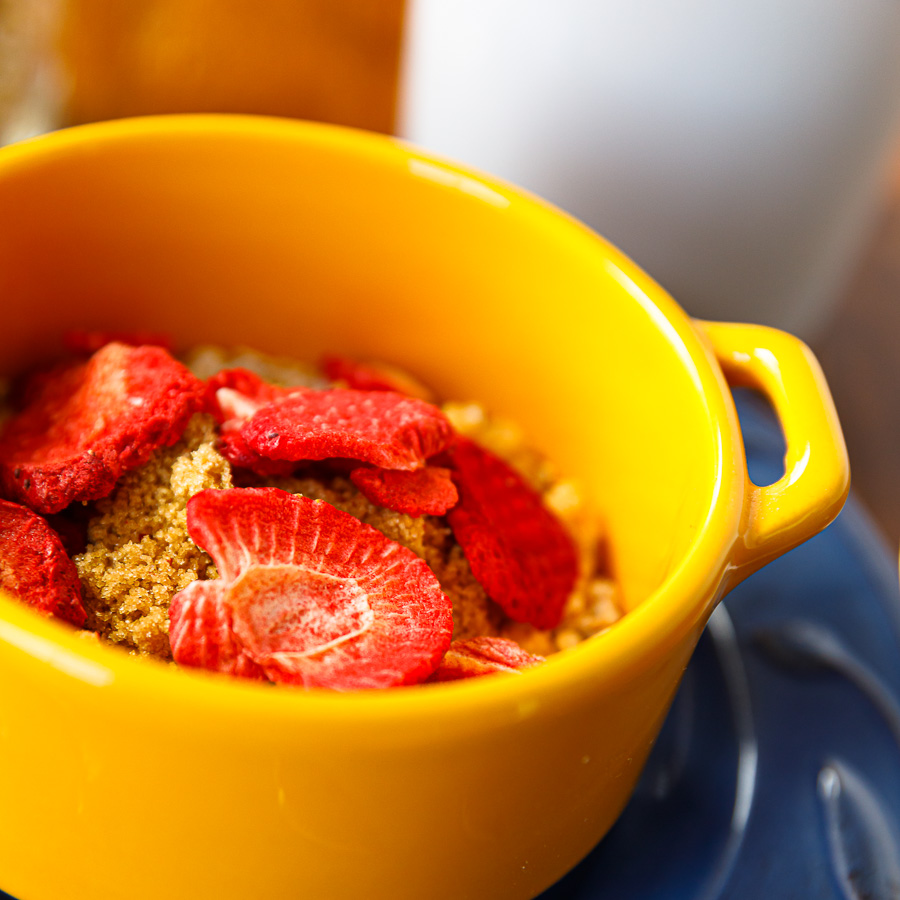 Instant oatmeal serving with dried strawberries in a yellow bowl.