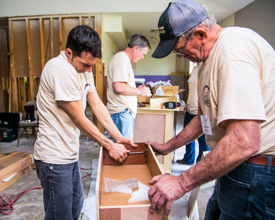 Four men volunteering with Eight Days of Hope put together drawers and cabinets.