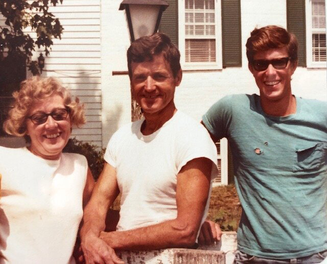 Joel Salatin in sunglasses stands smiling with his parents.