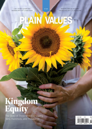 The July cover of Plain Values magazine, picturing a woman holding three sunflowers